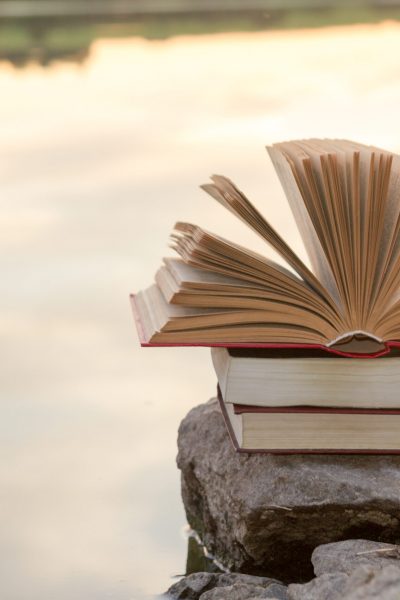 Stack of book and Open hardback book on blurred nature landscape backdrop. Copy space, back to school. Education background.